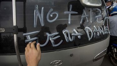 Un joven pinta un mensaje en contra de Daniel Ortega en el vidrio trasero de un vehículo en Managua, Nicaragua.