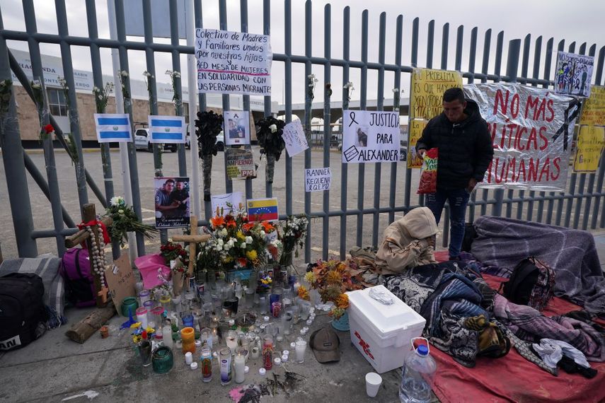 Un altar con velas y fotos cubre la cerca afuera del centro de detención de migrantes que fue el sitio de un incendio mortal, mientras los migrantes se despiertan después de pasar la noche en la acera en Ciudad Juárez, México, el jueves 30 de marzo de 2023.