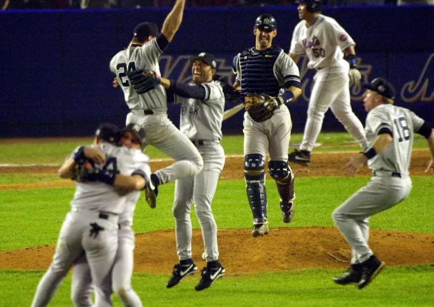 El primera base de los Yanquis de Nueva York, Tino Martínez (24), salta a los brazos del lanzador Mariano Rivera mientras el receptor Jorge Posada, tercero desde la derecha, Scott Brosius (18) y otros celebran después de derrotar a los Mets de Nueva York en el Juego 5 de la Serie Mundial para convertirse en campeones, el 26 de octubre de 2000, en el Shea Stadium de Nueva York.