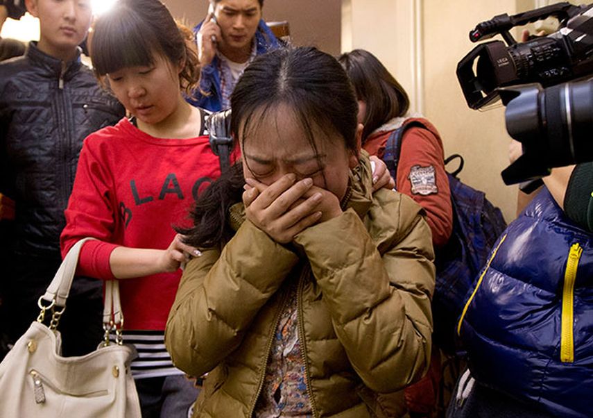 Un familiar (centro) de un ciudadano chino que viajaba en el avión de Malaysia Airlines llora mientras una mujer la acompaña al salir de una habitación de hotel para los familiares de los pasajeros, en Beijing, China. (Foto AP/Andy Wong)