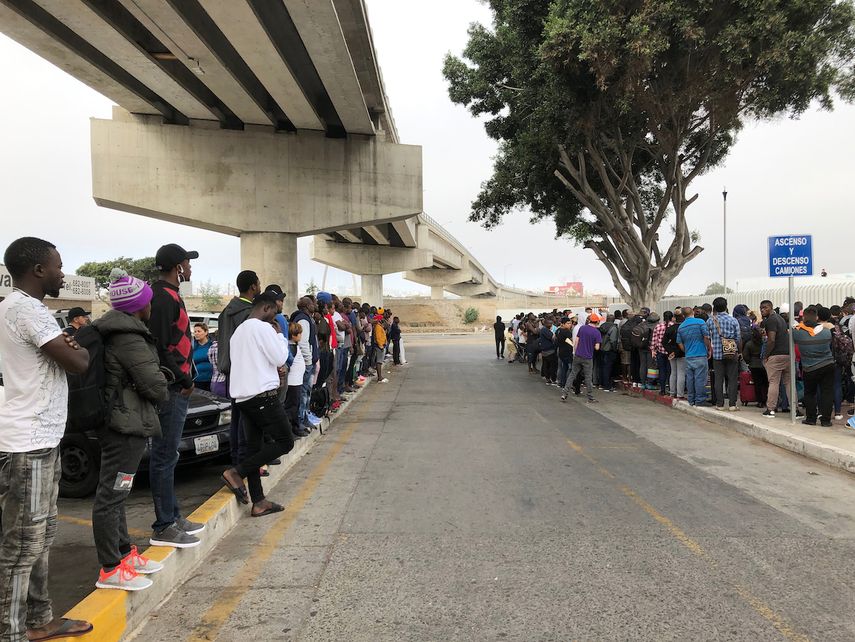 Decenas de migrantes escuchan expectantes en Tijuana, México, los nombres de quienes son llamados para que puedan iniciar una solicitud de asilo en Estados Unidos el 26 de julio del 2019.&nbsp;