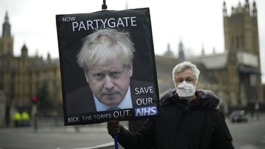 &nbsp;Un manifestante contrario al Partido Conservador sostiene una pancarta con la imagen del primer ministro británico, Boris Johnson, que alude a un escándalo sobre fiestas durante la cuarentena, ante el Parlamento en Londres, el miércoles 8 de diciembre de 2022.&nbsp;