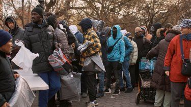 Migrantes toman mantas cerca de un Centro de Ayuda a Migrantes en la escuela primaria St. Brigid, en Nueva York.