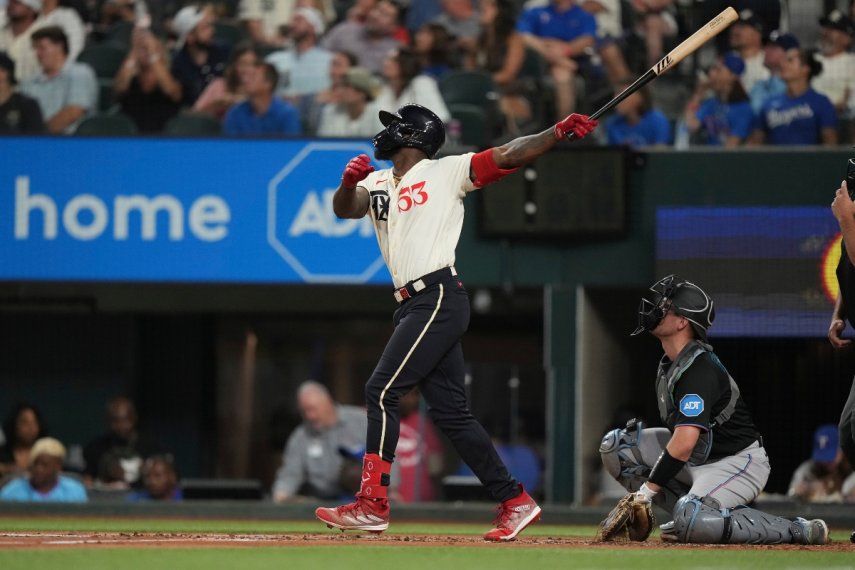 Adolis García (53), de los Rangers de Texas, y el receptor de los Marlins de Miami, Nick Fortes, observan el jonrón solitario de García durante la tercera entrada del juego de béisbol en Arlington, Texas, el viernes 4 de agosto de 2023.