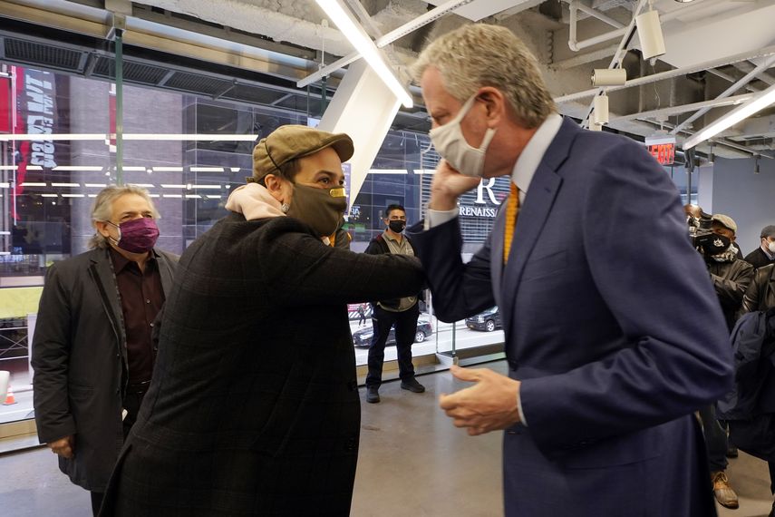 El actor Lin-Manuel Miranda, centro, y el alcalde de Nueva York Bill de Blasio se saludan con los codos antes de hacer un recorrido en la inauguración del centro de vacunación COVID-19 Broadway en Nueva York el lunes 12 de abril de 2021.&nbsp;