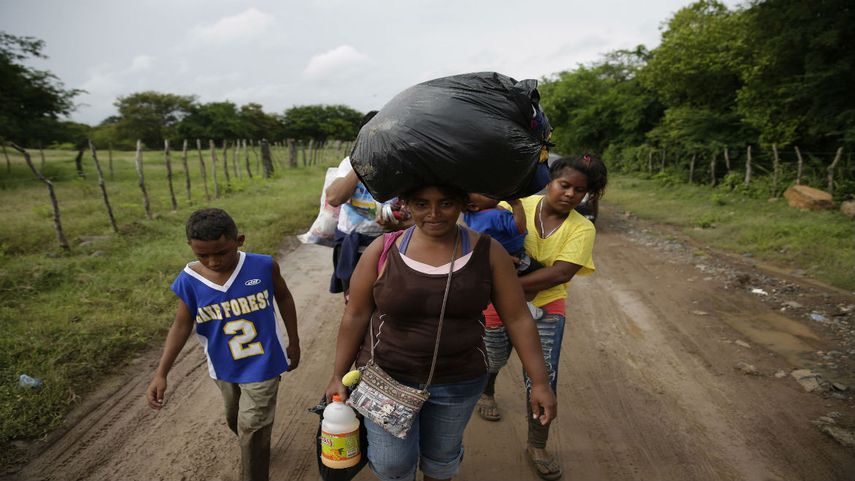 Un familia de migrantes centroamericanos pasa por la frontera entre Honduras y El Salvador en su camino hacia EEUU.