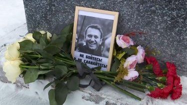 En esta imagen tomada de un video, se muestran las flores y una foto del líder opositor ruso Alexéi Navalni depositados por su madre, Lyudmila Navalnaya, en su memoria en un monumento a las víctimas de la represión política, en Salekhard, a 1937 kms (1211 millas) al noreste de Moscú, Rusia, el 20 de febrero de 2024.