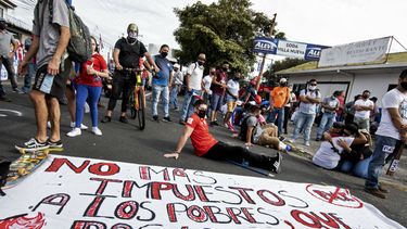 La gente se manifiesta junto a un cartel que dice No m&aacute;s impuestos a los pobres, haz que los ricos paguen, contra la moci&oacute;n del gobierno de aumentar los impuestos para llegar a un acuerdo crediticio con el Fondo Monetario Internacional (FMI), frente a la casa presidencial en San Jos&eacute;, el 12 de octubre de 2020.