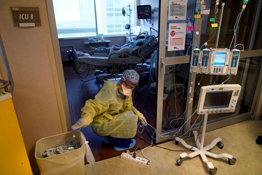 Una enfermera de terapia intensiva mueve cables de máquinas médicas afuera de la habitación de un paciente con COVID-19, en el centro médico de Willis-Knighton, en Shreveport, Luisiana.