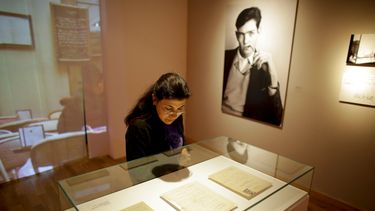 Una mujer mira páginas escritas a mano por el escritor Julio Cortázar, cerca de una fotografía del autor, en una exhibición que conmemora el centenario de su nacimiento en el Museo Nacional de Bellas Artes en Buenos Aires, Argentina, el martes 26 de agosto de 2014.