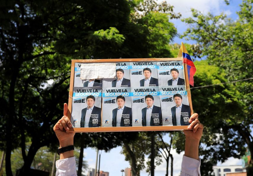Un hombre sostiene un cartel con propaganda del candidato presidencial Miguel Uribe durante una protesta contra la violencia y a favor de la paz en Medellín, Colombia, el 8 de junio de 2025, un día después del ataque a Uribe. Un destacado candidato presidencial colombiano de derecha, que recibió un disparo durante un acto de campaña en Bogotá, fue sometido con éxito a una primera cirugía, según informó el alcalde de la ciudad el domingo. El senador Miguel Uribe, de 39 años, se dirigía a sus simpatizantes en la capital cuando un hombre armado le disparó dos veces en la cabeza y una vez en la rodilla antes de ser detenido.