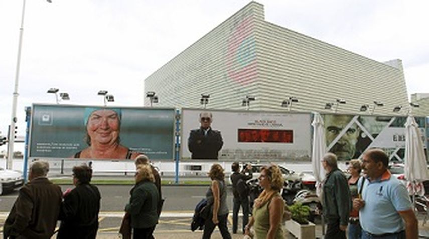 Varias personas pasan ante los carteles del Festival Internacional de Cine de San Sebastián. (EFE)