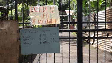 Un letrero en el que se exige el uso de mascarilla durante la pandemia de COVID-19 cuelga en un portón a la entrada de una zona habitacional en Managua, Nicaragua, el jueves 9 de septiembre de 2021. Otros letreros anuncian la venta de cigarrillos, huevo, cerillos, leche y café.&nbsp;