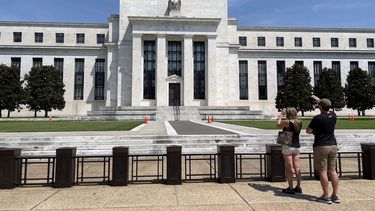 Dos personas toman fotos de la sede de la Reserva Federal en Washington.