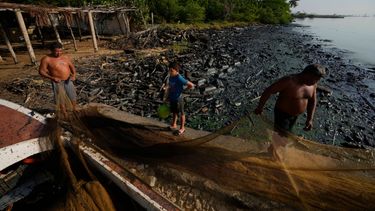 Pescadores estiran sus redes en la ribera del Lago de Maracaibo contaminado con petróleo y desechos en el agua.