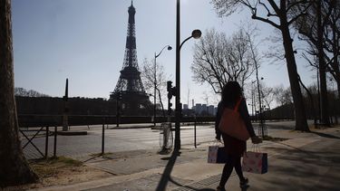 Una mujer camina en una calle vacía cerca de la Torre Eiffel durante un confinamiento a nivel nacional para frenar la propagación del nuevo coronavirus, en París, el jueves 26 de marzo de 2020. 