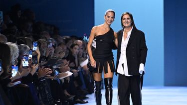 La diseñadora de moda italiana Maria Grazia Chiuri saluda a la audiencia con la artista italiana Sagg Napoli después de la presentación de Dior de la colección de prêt-à-porter femenino primavera-verano 2025 como parte de la Semana de la Moda de París, en París el 24 de septiembre de 2024. 