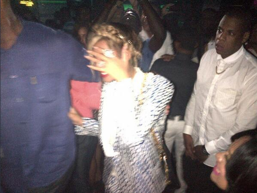 La cantante Beyoncé se cubre el rostro durante su visita junto a su marido Jay-Z, vestido de blanco, a una discoteca de República Dominicana. (TWITTER)