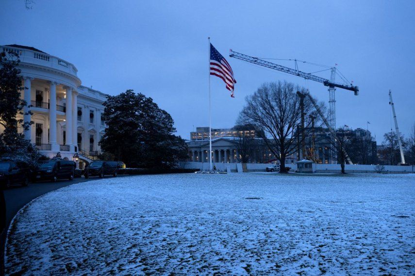 El edificio del Departamento del Tesoro de Estados Unidos (R) se ve detrás del sitio de construcción del nuevo salón de baile que reemplaza al Ala Este de la Casa Blanca en una noche nevada en Washington, DC.