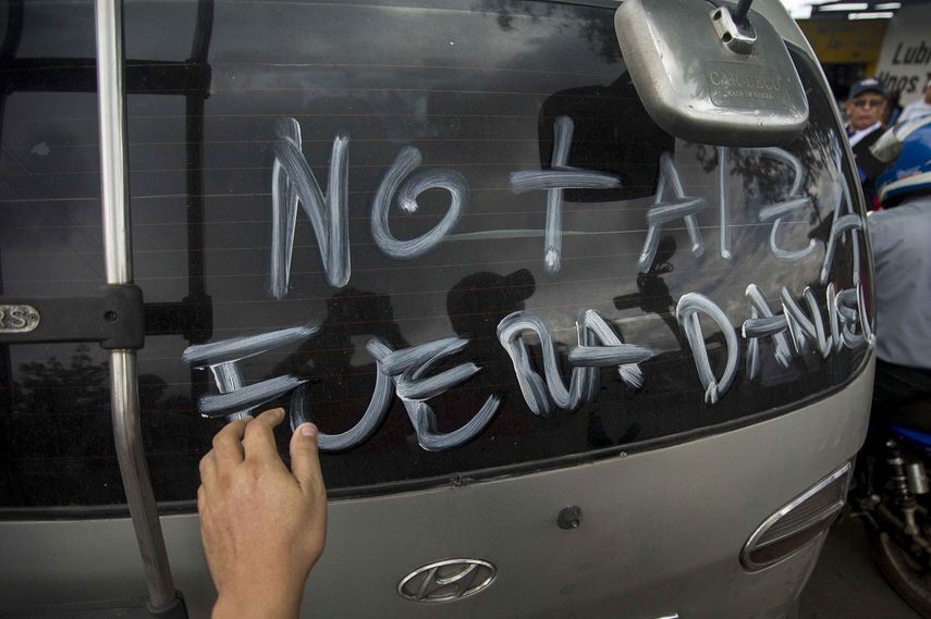 Un joven pinta un mensaje en contra de Daniel Ortega en el vidrio trasero de un vehículo en Managua, Nicaragua.