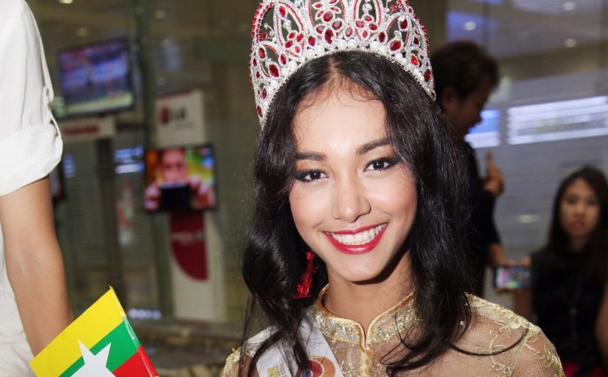 La modelo de Mianmar May Myat Noe, ganadora del certamen Miss Asia Pacífico Mundo 2014, ondea una pequeña bandera de su país a su llegada al aeropuerto internacional en Yangon, Mianmar. (AP)