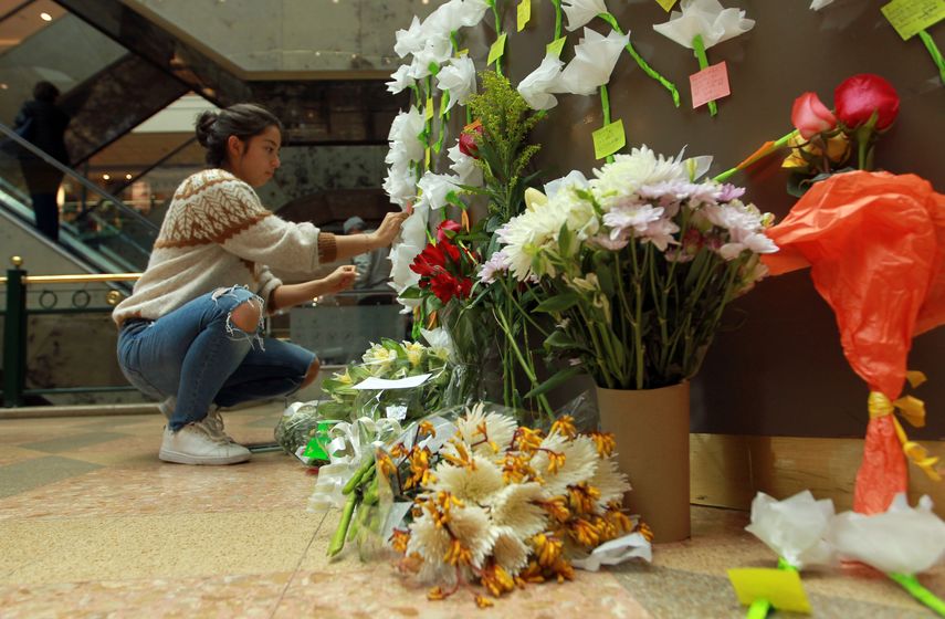 Una mujer se acerca a rendirle tributo a las víctimas en las instalaciones del centro comercial Andino en Bogotá.
