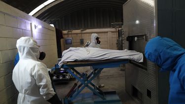 Trabajadores con equipo de protecci&oacute;n meten el cuerpo de una persona que muri&oacute; de complicaciones derivadas del nuevo coronavirus a un horno para ser cremado en el Mausoleo San Cristoal en Ecatepec, M&eacute;xico, el jueves 21 de mayo de 2020.