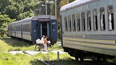 Fotografía de archivo fechada en agosto de 2018 de dos personas que caminan entre dos vagones de un tren de pasajeros en las inmediaciones de una estación de trenes en La Habana, Cuba.