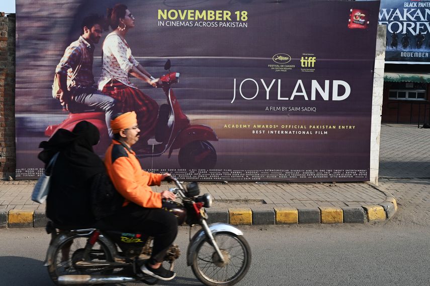 Una pareja pasa junto a una pancarta promocional de la película Joyland, producida en Pakistán, que se exhibe frente a un cine en Lahore el 16 de noviembre de 2022.