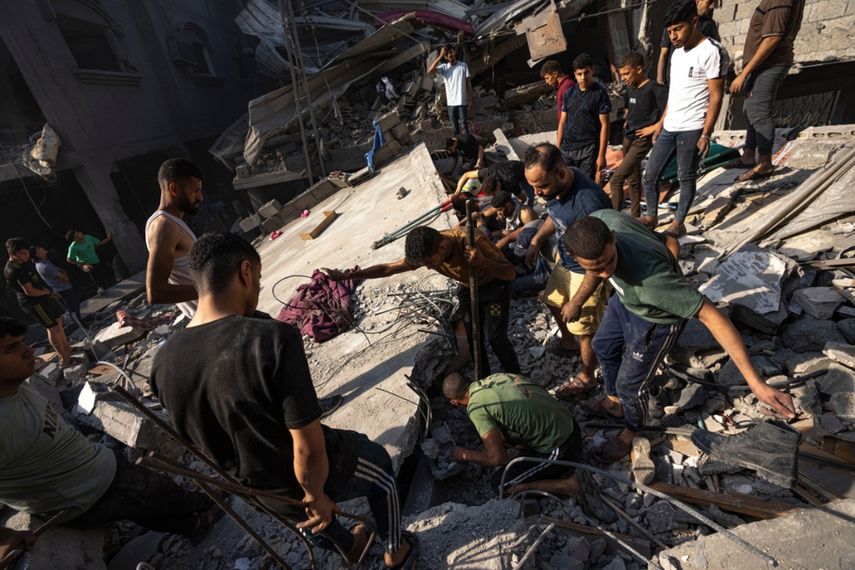 Palestinos buscan cadáveres y sobrevivientes entre los restos de un edificio residencial, tras un ataque aéreo de Israel en Al Shati, el 12 de octubre de 2023.
