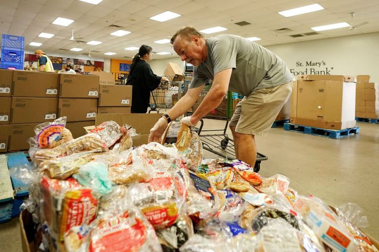 Voluntarios llenan carros de supermercado con alimentos para distribuirlos en el Banco de Alimentos St. Mary