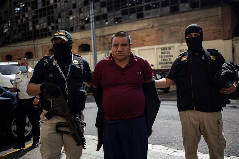 Juan Gutiérrez Castro es escoltado con esposas a la corte tras ser detenido durante una operación policial contra presuntos traficantes de migrantes en la Ciudad de Guatemala, el martes 2 de agosto de 2022. 