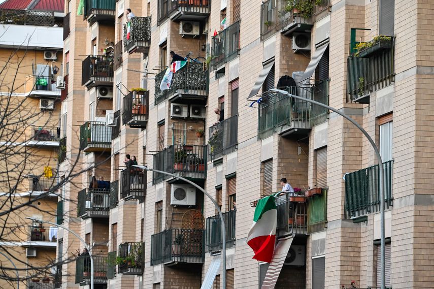 Varios residentes de un edificio muestran la bandera italiana este domingo durante la cuarentena.