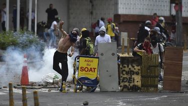Un manifestante lanza una piedra a los agentes de la policía antidisturbios durante una protesta contra el gobierno en Cali, Colombia.