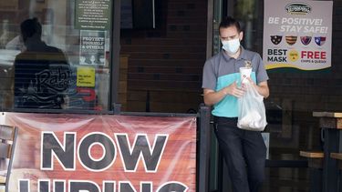 Una persona pasa junto a un letrero que solicita empleados en un restaurante en Texas.