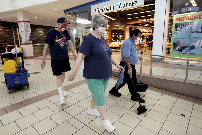 Una pareja con mascarillas camina frente a un trabajador de limpieza en el centro comercial Gateway, en Lincoln, Nebraska, el viernes 1 de mayo de 2020.&nbsp;