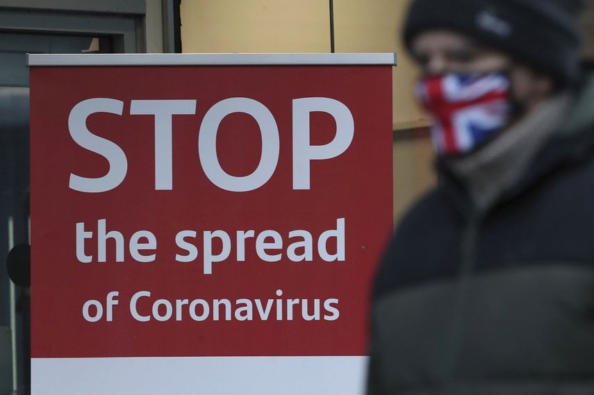 Una persona pasa frente a a un letrero que pide frenar la diseminación del coronavirus afuera de un banco en Glasgow, Escocia, el 5 de enero de 2021.&nbsp;