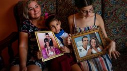 Danmara Triana (izquierda), con sus hijas Alice (centro) y Claudia, muestran fotos suyas con su hermano y su padres, quienes se mudaron a EEUU en 2015, en su casa en Cienfuegos, Cuba.