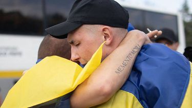 Prisioneros de guerra ucranianos, envueltos en banderas nacionales ucranianas, se abrazan tras un intercambio en un lugar no revelado, durante la invasión rusa de Ucrania. Rusia y Ucrania el 9 de junio de 2025.