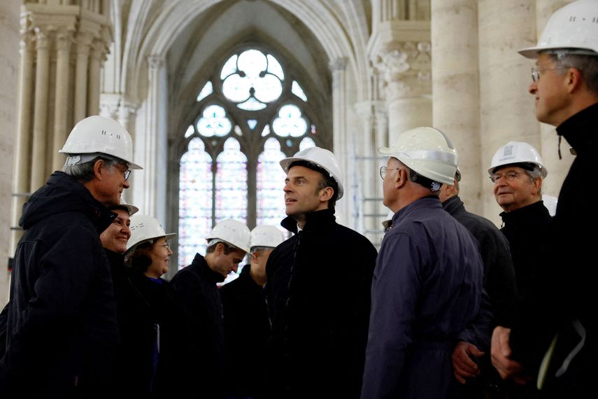 El presidente francés, Emmanuel Macron, con un casco de trabajo, habla con expertos en conservación mientras visita el sitio de restauración en la catedral de Notre-Dame de París, que resultó dañada en un devastador incendio hace cuatro años, el 14 de abril de 2023.