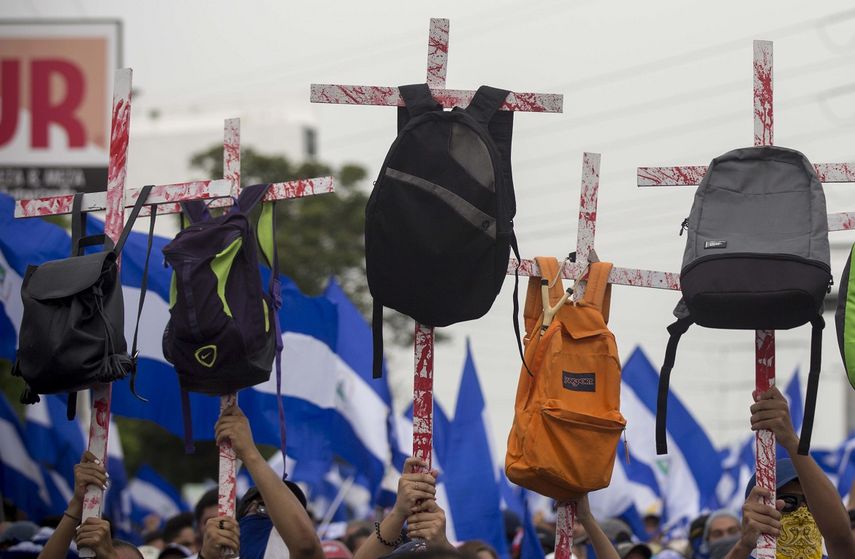 Varios jóvenes sostienen unas cruces con mochilas en honor a los estudiantes que murieron en las pasadas manifestaciones contra Daniel Ortega.