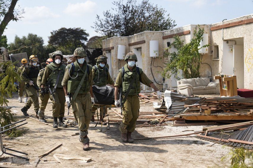 Soldados cargan cadáveres de israelíes asesinados en el kibutz Kfar Azza, Israel, el martes 10 de octubre de 2023. Militantes de Hamás invadieron Kfar Azza, el sábado, donde muchos israelíes fueron asesinados y hechos cautivos. 