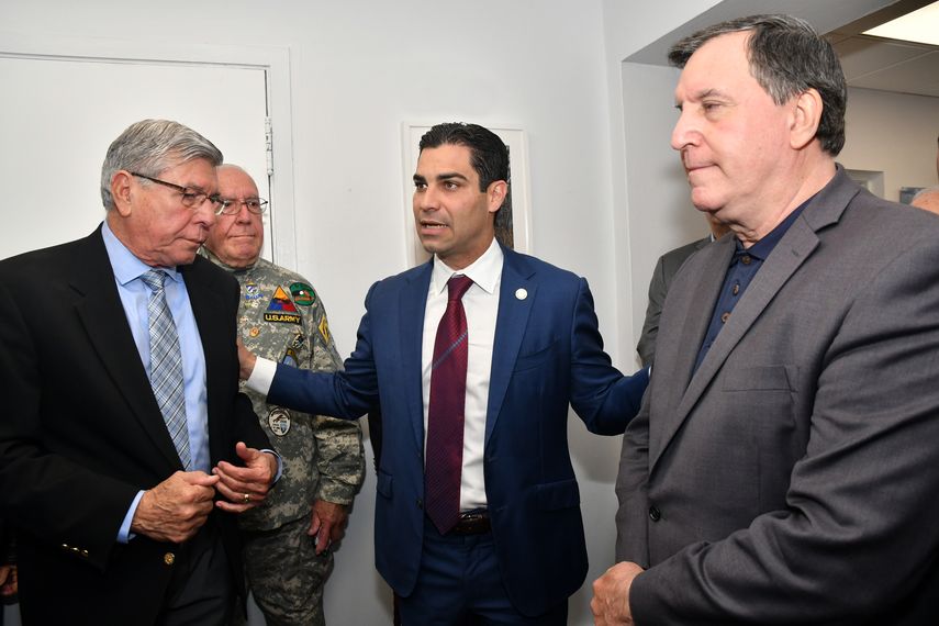 Francis Sua´rez, en el centro, conversa con Manolo reyes (izq.) y Joe Carollo (der.), tras colocar la bandera enmarcada de la Brigada 2506 en su despacho.