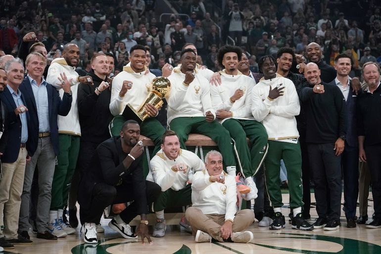 Los dueños y jugadores de los Bucks de Milwaukee posan con sus anillos de campeones de la NBA, antes de inaugurar la nueva temporada el martes 19 de octubre de 2021, enfrentando a los Nets de Brooklyn