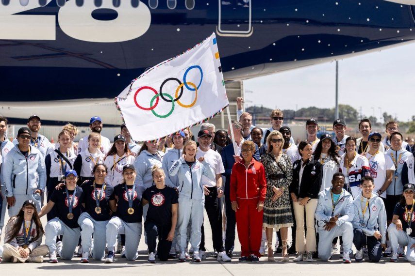 Atletas olímpicos y oficiales posan para una foto con la alcaldesa de Los Ángeles, Karen Bass, y el gobernador Gavin Newsom mientras exhiben la bandera olímpica, el 13 de agosto de 2024.