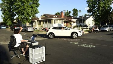 En esta fotograf&iacute;a del 9 de mayo de 2020 el m&uacute;sico Adam Chester, izquierda, saluda a un vecino que pasa en su auto mientras interpreta su concierto semanal en su barrio en la secci&oacute;n de Sherman Oaks en Los Angeles. Chester suele ser un sustituto de Elton John, canta y coca en los ensayos del super astro.&nbsp;