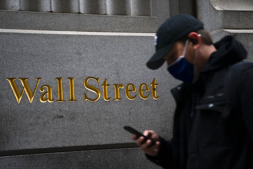 Un hombre revisa su teléfono celular frente a la sede de Wall Street.