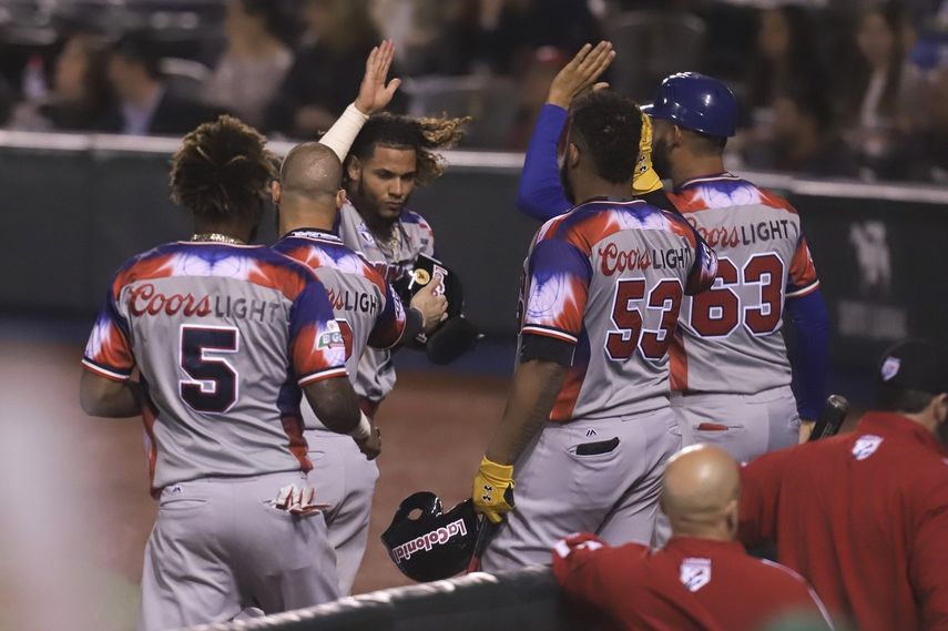 Jugadores de las Águilas Cibaeñas de República Dominicana festejan una anotación ante los Alazanes de Granma de Cuba.
