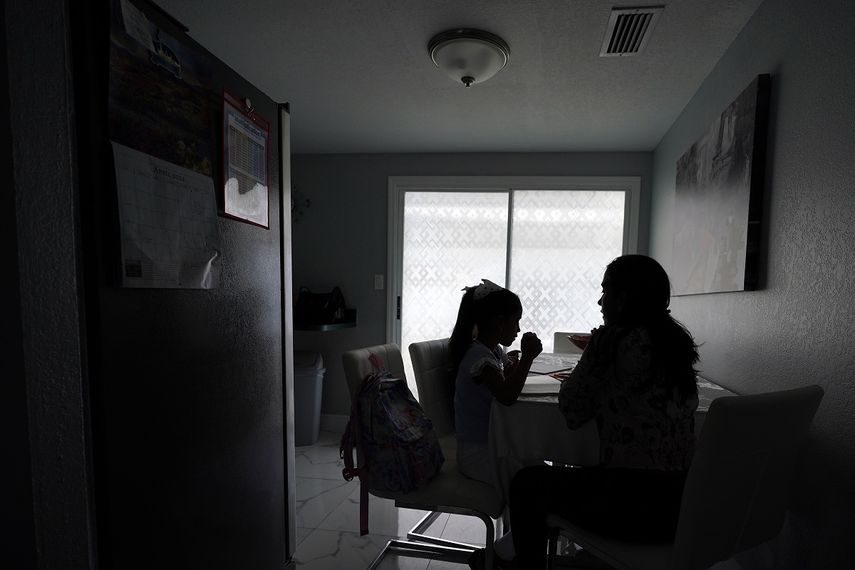 Una mujer ayuda a sus dos hijos con sus tareas en su casa, el martes 19 de abril de 2022 en Tampa, Florida.&nbsp;