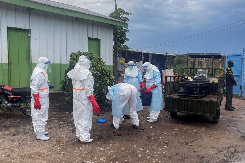 Personal médico con equipo de protección personal (EPP) se encuentra junto al ataúd de un paciente fallecido por ébola, sobre un remolque en un hospital de Rwampara el 21 de mayo de 2026.